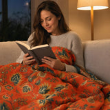 Woman reading cosily wrapped in the marigold throw blanket at dusk